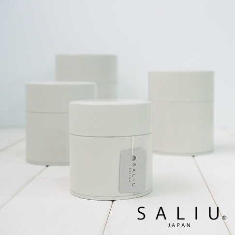 四個簡約風格的白色錫製茶葉罐，其中一個罐子掛有灰色吊牌，上面印有「SALIU DESIGN」字樣。