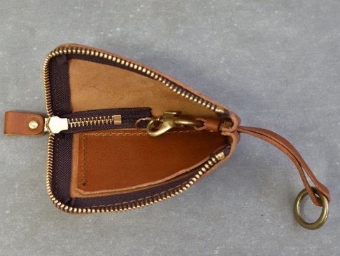 職人手作皮革Organ抽繩收納鑰匙包，採用棕色皮革製作，設有黃銅色拉鍊、掛鉤和鑰匙圈。內部有皮革隔層，整體風格簡約實用。