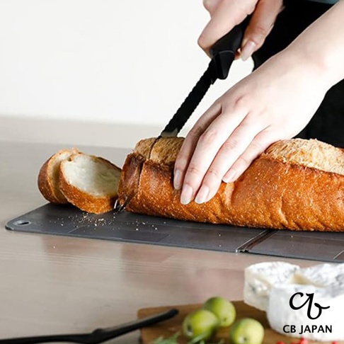 CB JAPAN 品牌 logo 標誌，旁邊是「CB JAPAN」字樣，下方是切好的麵包和起司，旁邊有綠色的小水果。