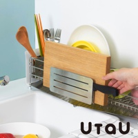 不鏽鋼瀝水架上放置著一個木質砧板，旁邊有木勺、筷子、碗盤和刀具。