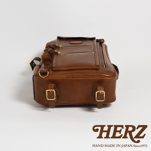 職人手作皮革兩用多功能後背包 R-66，採用溫潤的棕色皮革，設計簡約，配有金屬拉鍊與扣環，展現經典風格。