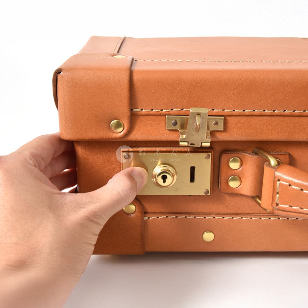 職人手作皮革英倫風便攜手提行李箱 TR-1，採用經典棕色皮革，配有黃銅色鎖扣、鑰匙孔和鉚釘，手工縫線精緻。