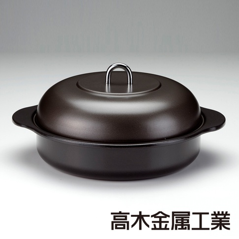 一個帶有銀色提環的深棕色鑄鐵萬用鍋，鍋蓋呈圓頂狀，鍋身有兩個黑色把手。