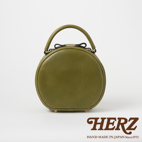 日本HERZ手工皮革圓形斜背包，綠色，配有金色拉鍊和品牌標誌。