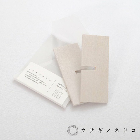 淺色木質立方塊置物架，兩塊木頭可組合，帶有卡槽設計，旁邊有產品說明卡片，背景為白色布料。