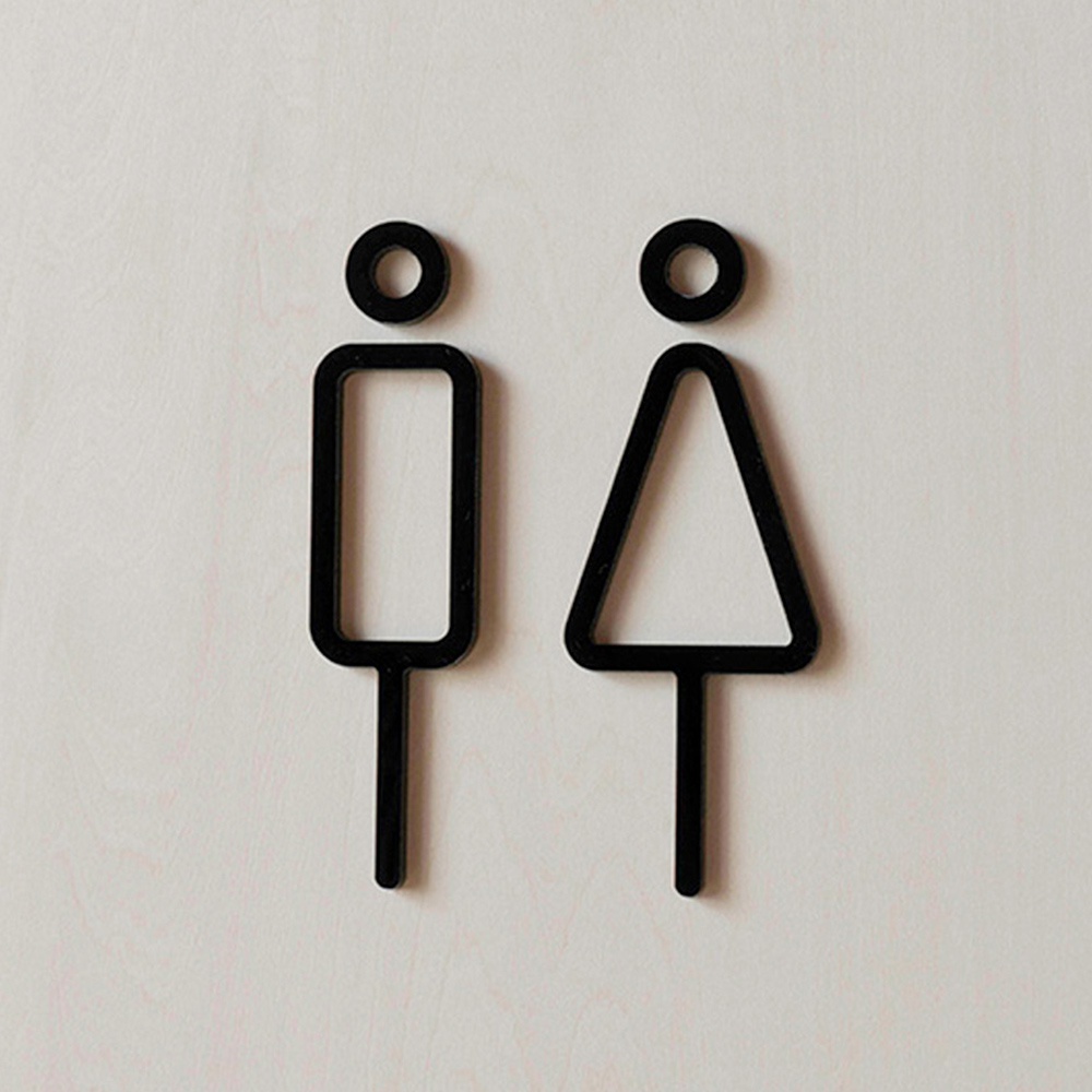 兩個黑色簡約風格的男女廁所標示牌，分別由圓形頭部和長方形（男性）或三角形（女性）身體組成，皆有垂直的腿部，安裝於淺木紋背景上。