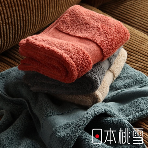 堆疊的今治匹馬棉毛巾，呈現珊瑚橘、炭灰色、米白色與藍綠色。毛巾材質蓬鬆柔軟，邊緣有滾邊設計。