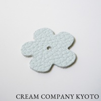 淺藍色皮革製成的五瓣花形吊飾，表面有細緻紋理，中央有圓孔。