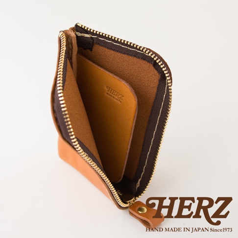 日本HERZ職人手作皮革分隔收納迷你錢包，採用天然皮革製作，呈L型拉鍊開口設計，內部設有皮革隔層，皮革表面印有HERZ MADE IN JAPAN字樣，整體呈現簡約質感風格。