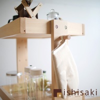 淺色木製收納推車，有兩層層架，側邊掛著米白色布料物品，上方層架擺放著玻璃罐和深棕色布料收納盒。