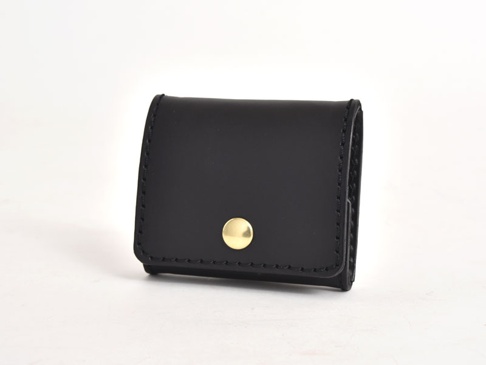 黑色皮革箱型零錢包，有金色按鈕開合，縫線整齊。