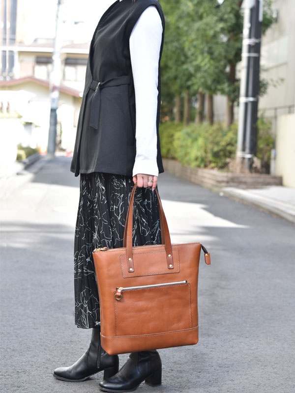 棕色皮革直式拉鍊托特包，設有正面拉鍊口袋和頂部拉鍊開合，搭配雙提把。