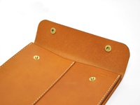 職人手作皮革信封式雙釦手拿袋，展示袋蓋與袋面，採用棕色皮革材質，設有兩個金色金屬按釦，搭配白色車縫線。