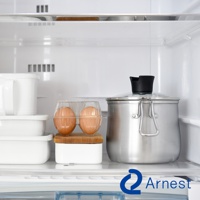 逸品物創不鏽鋼三合一萬用料理鍋，鍋身為銀色不鏽鋼材質，帶有玻璃鍋蓋和黑色提把。鍋旁有透明雞蛋盒裝著兩顆雞蛋，以及白色儲物盒。