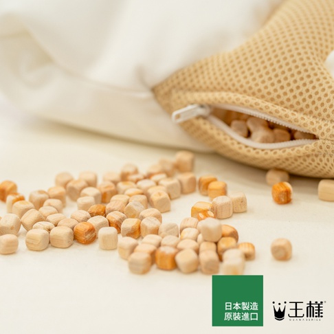 許多檜木塊散落在白色布料上，一個網狀材質的棕色枕頭敞開拉鍊，露出內部的檜木填充物，右下角有「日本製造 原裝進口」及「王樣 OSAMA SERIES」的標誌