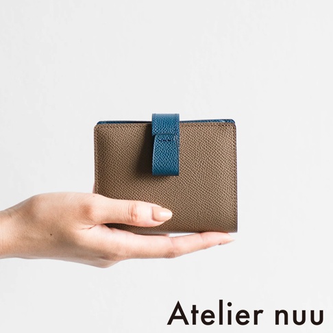 Atelier nuu 品牌 logo，下有棕色皮革雙折短夾，由手托著