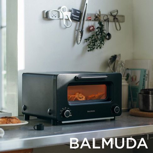 The Toaster Pro 蒸氣烤麵包機 專業版 K11C-SE，黑色機身，設有玻璃門，內有正在烘烤的麵包。機身側面和頂部有金屬配件，整體呈簡約設計風格。