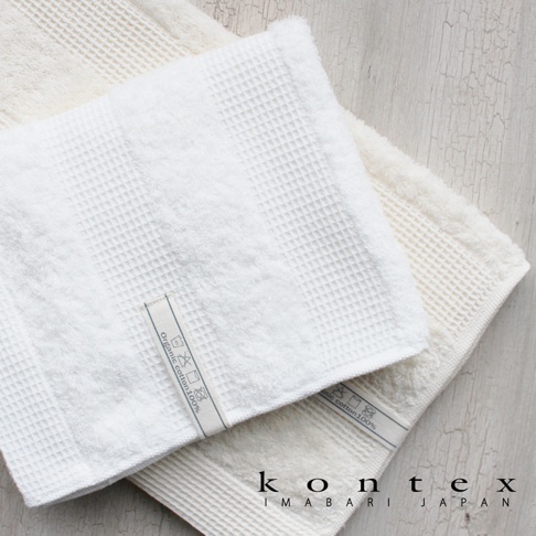 兩條日本今治 WAFFLE BORDER 有機棉毛巾，其中一條為白色，另一條為淺米色，皆為鬆餅紋織法，材質標籤顯示有機棉 100%。
