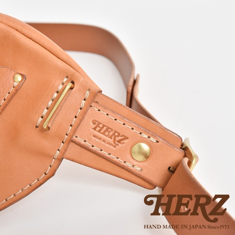 HERZ 職人手作皮革斜背包，展示其製作細節，包含壓印品牌 logo 及 made in Japan 字樣，以及黃銅五金配件