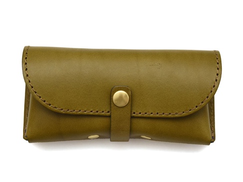 橄欖綠皮革製成的職人手作眼鏡收納盒，帶有金屬按扣和扣帶，以及手工縫線細節，適合收納眼鏡。