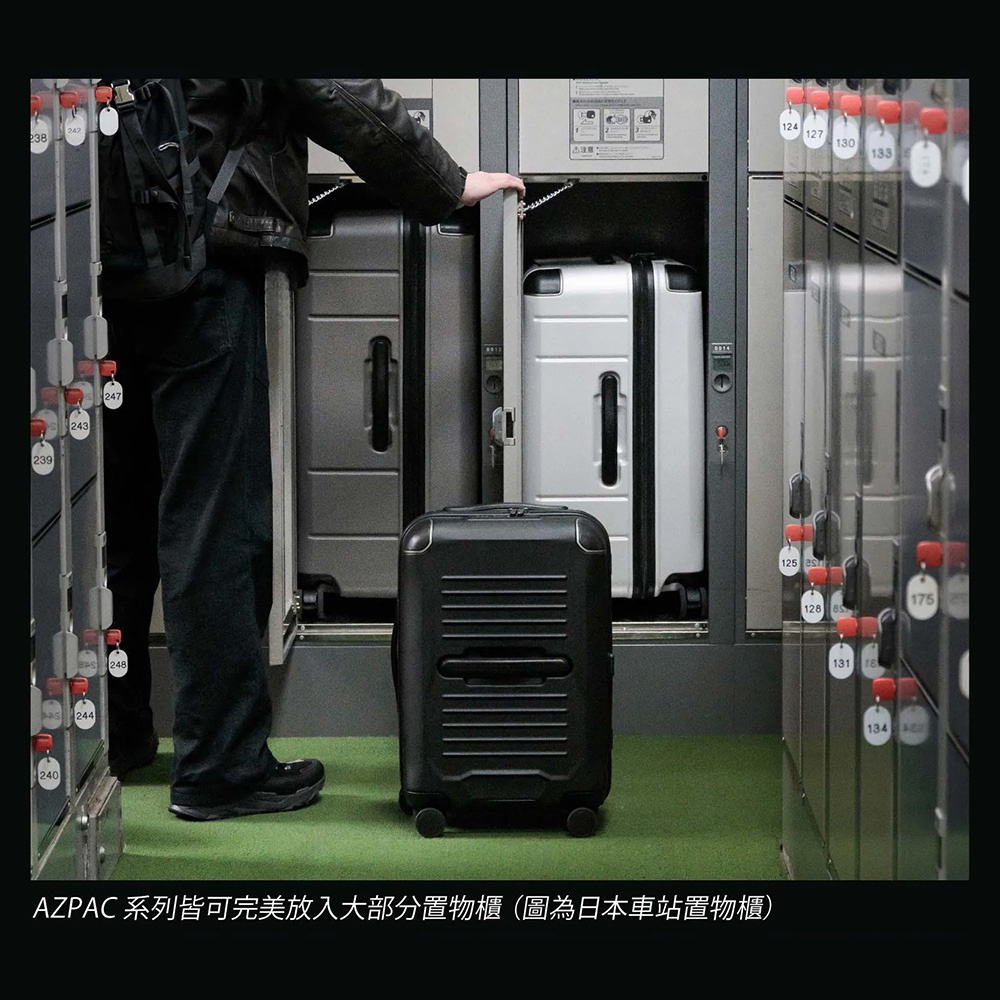 一名穿著黑色外套與深色褲子的男子正站在置物櫃前，將一個銀色行李箱放入櫃中，地面上則放置著一個黑色的AZPAC行李箱，展示該品牌行李箱能完美放入日本車站置物櫃的空間特性。