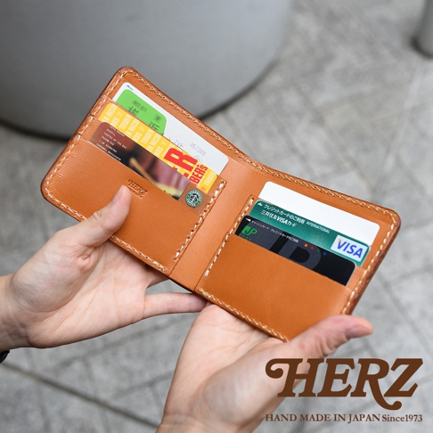 職人手作的棕色皮革二折橫式小短夾，內含多個卡槽，展示有信用卡、會員卡及紙鈔。