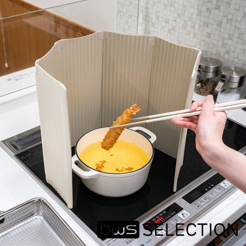 淺米色六片式摺疊防油隔板，設有垂直紋路，放置於白色燉鍋旁，鍋內裝有炸物的淺黃色油。一隻手持白色筷子夾著一隻炸蝦。