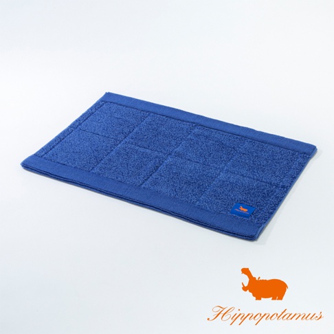 藍色竹棉浴墊，表面有方形格紋，邊緣有縫線裝飾，左下角有一個橙色標籤，上面印有白色鴨子圖案。