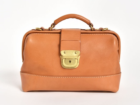 職人手作皮革兩用迷你口金單肩包，採用溫潤的棕褐色皮革，配有復古黃銅色鎖扣和金屬環，頂部有短提把，整體風格簡潔大方。