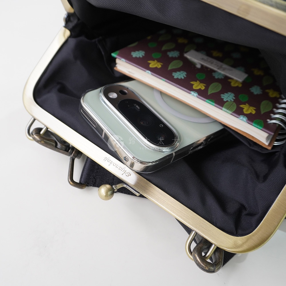 AYANOKOJI Sarei 機能布直式口金斜背包內部，可見手機和一本封面有葉子圖案的筆記本。