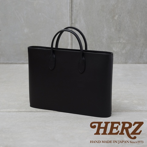 職人手作黑色皮革Organ薄型公事包，簡潔的長方形設計，搭配雙提把，以精緻車縫線勾勒出俐落線條，展現皮革的質感。