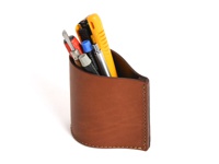 職人手作皮革筆筒，採用棕色皮革製成，設計簡潔，可收納多支筆及工具，例如黃色美工刀、螺絲起子和筆。