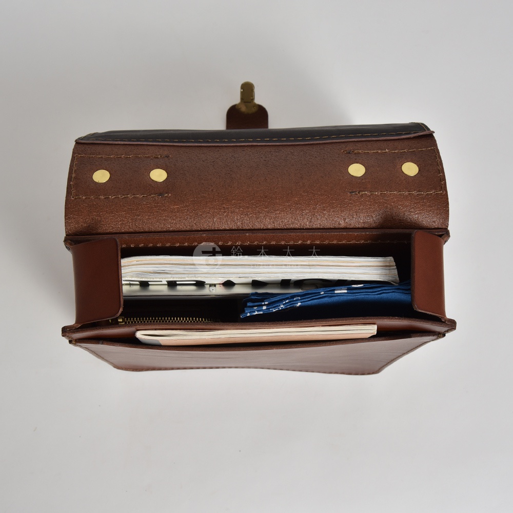 職人手作皮革後背包，棕色皮革，內部裝有筆記本和藍色印花布料，頂部翻蓋設計，附有黃銅釦件。