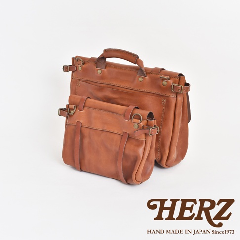 兩款棕色皮革復古郵差包，一個較大，一個較小，均採用水洗加工處理，配有金屬扣環和皮革帶。