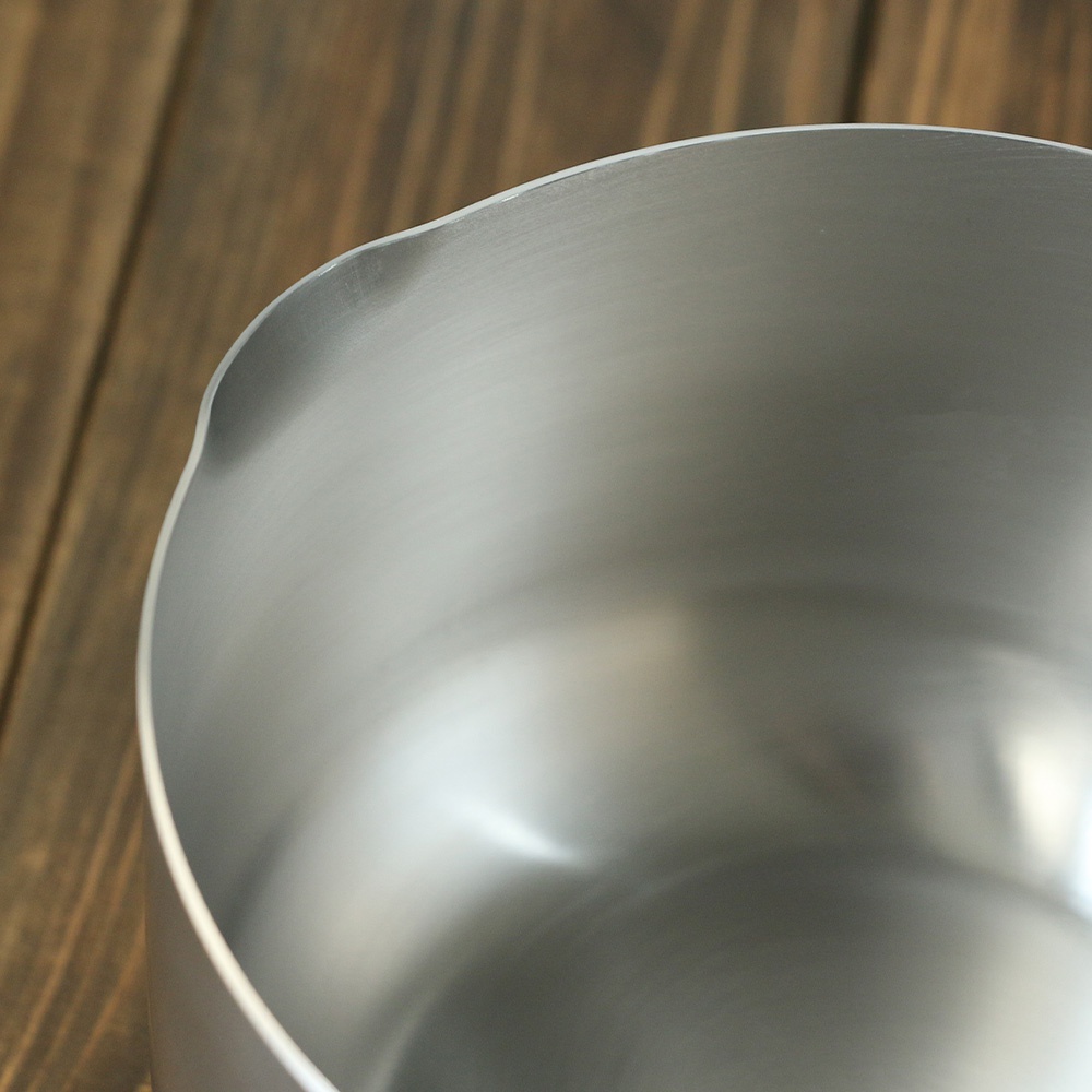 不鏽鋼雙口牛奶鍋，鍋身為銀色，材質為不鏽鋼。鍋緣有兩個出水口設計，表面光滑，有細微的髮絲紋路。