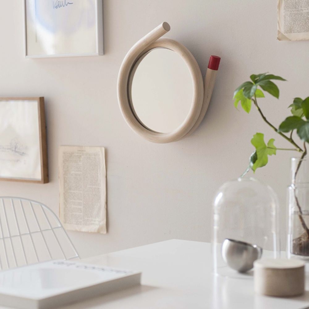 圓形鏡子，邊框由淺木色藤編材料製成，彎曲成獨特的造型，一端頂部有紅色裝飾。