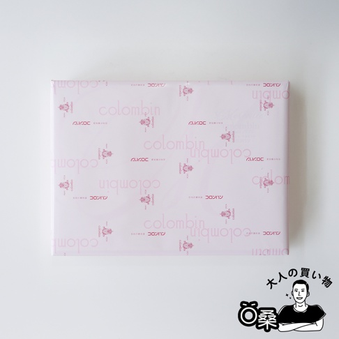 Colombin 品牌綜合巧克力夾心餅乾禮盒，粉色包裝紙印有品牌名稱和日文，右下角為一人快樂購物示意圖。