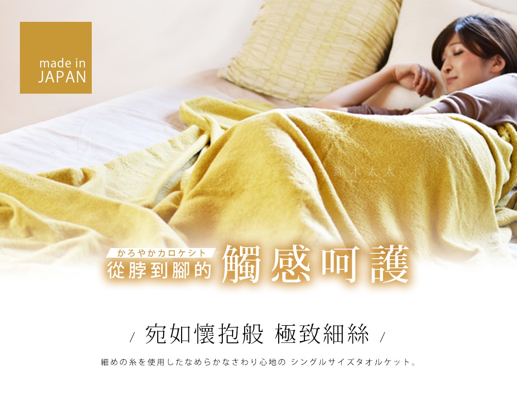 一條芥末黃色的今治毛巾被，質地柔軟，蓋在床上，一位女性依偎在床邊，被毛巾被覆蓋。