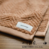 ECOR 天然系人字紋有機棉毛巾，呈現溫暖的淺棕色調，材質柔軟，帶有清晰的人字紋織法和品牌標籤「SUIFUTOSHA」。