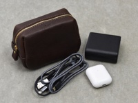 職人手作咖啡色皮革Organ拉鍊收納包，配有金色拉鍊，旁邊放置一個黑色充電器、一條灰色編織充電線及一個白色無線耳機充電盒。