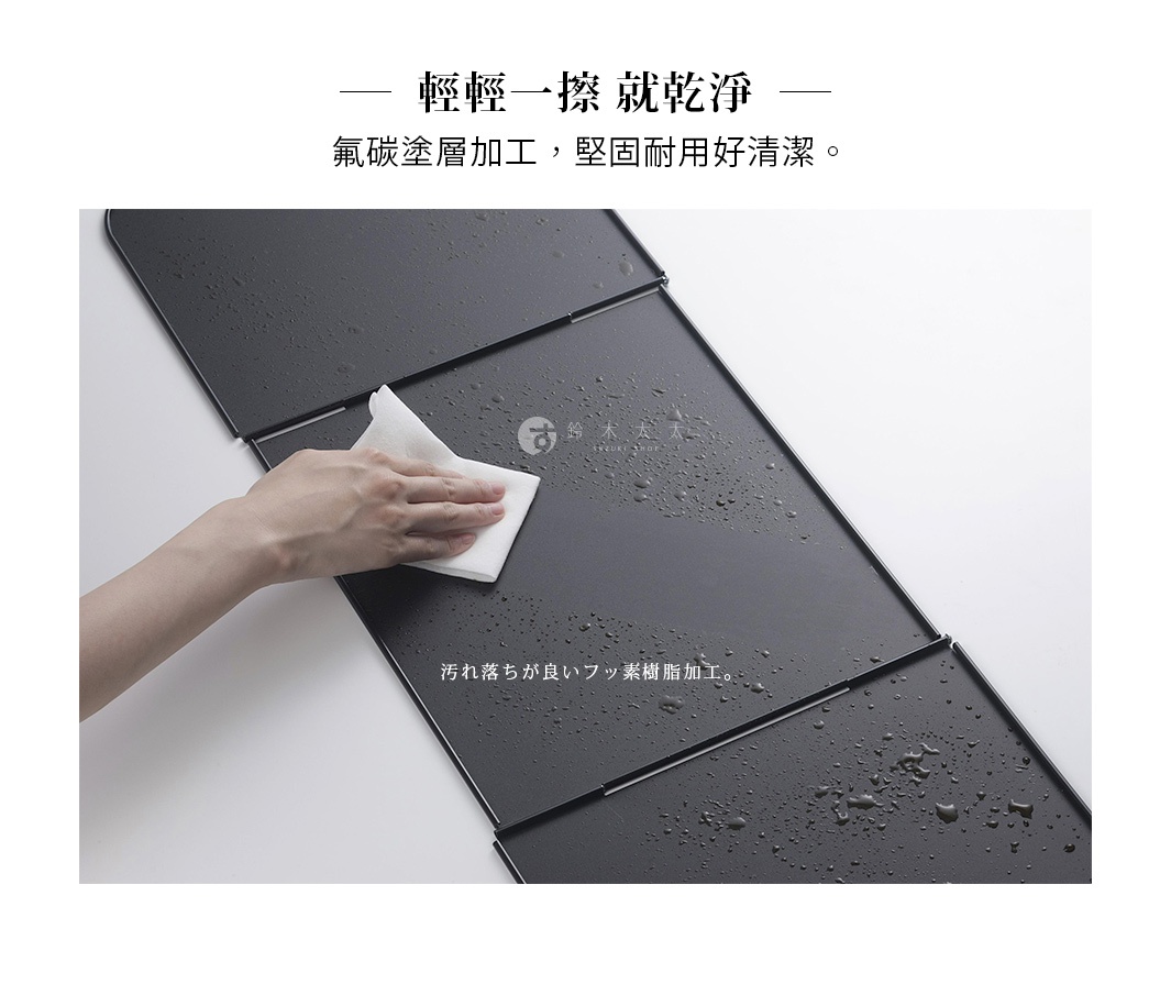 深灰色ㄇ型折疊防汙擋油板，表面有水滴和油漬，一隻手正用白色濕紙巾擦拭。