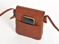 職人手作皮革直式隨行袋，咖啡色皮革，正面有手機收納袋，袋身縫線明顯，附有細皮革背帶。