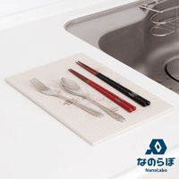 淺色珪藻土置物墊，表面有細緻的條紋，上面放著一把銀色湯匙、一把銀色叉子，以及一雙紅色和一雙黑色的筷子。