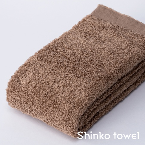 MAISON BLANC 輕奢柔膚匹馬棉浴巾，呈現溫暖的棕褐色，質地蓬鬆柔軟，邊緣有細緻的織紋。