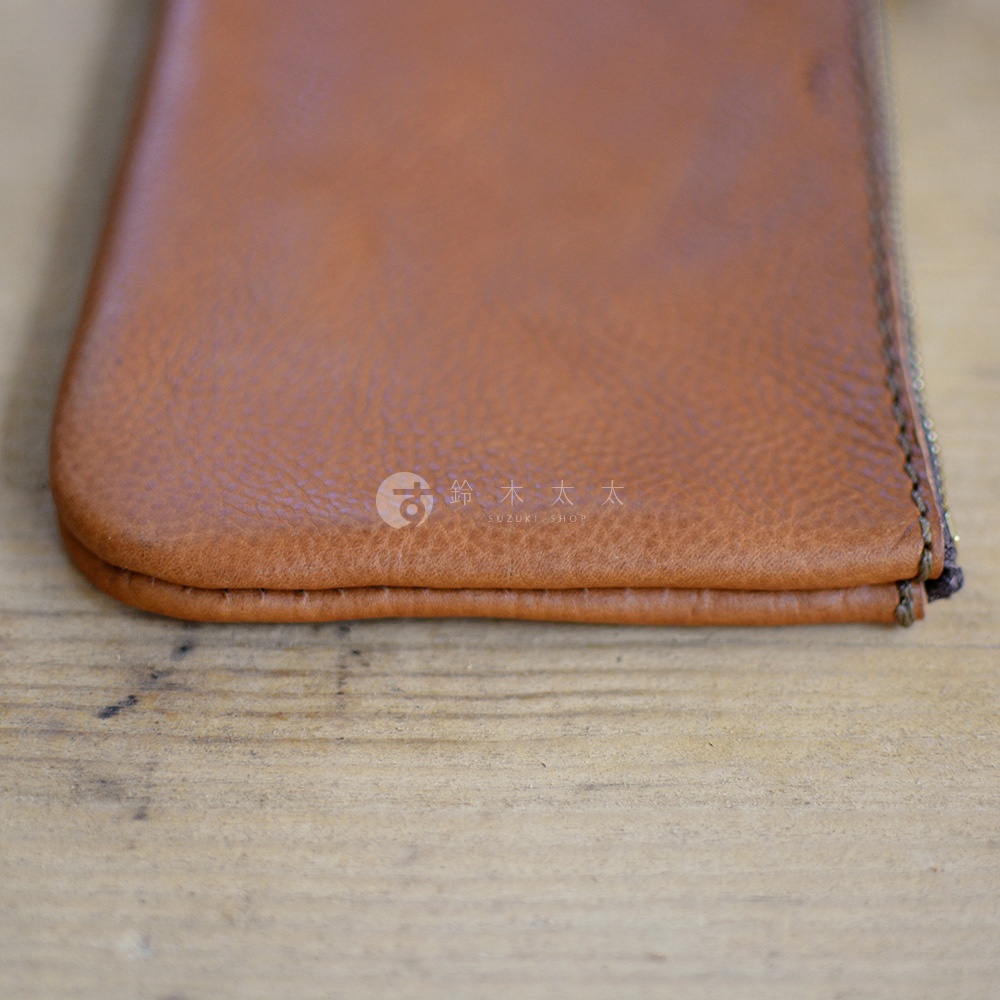 職人手作皮革Organ拉鍊式小物收納袋，呈現溫潤的棕色皮革質感，側邊縫線精緻，拉鍊部分可見金屬細節。