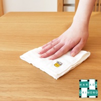 一條白色精緻繡花擦拭巾，繡有黃色蜂蜜罐圖案，置於木質桌面上，一隻手正輕柔地壓在擦拭巾上。