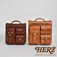 兩款職人手作皮革三口袋三用後背包，一款為深棕色，另一款為淺棕色。兩款背包均採用天然皮革製成，設有頂部提把、拉鍊開口、多個翻蓋口袋，並以金屬扣環和車縫線裝飾。