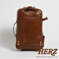 棕色皮革製成的職人手作後背包，具備雙肩帶及手提把，側面有拉鍊和口袋，底部有金屬扣環。