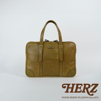 橄欖綠皮革公事包，雙提把設計，正面有翻蓋口袋及金屬扣環裝飾，可肩背或手提。