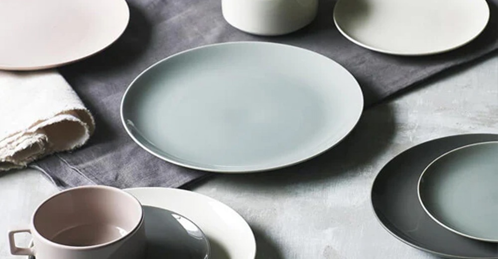 簡約素雅的圓形餐盤，呈現柔和的淡藍色、粉色、白色及深灰色，材質為美濃燒陶瓷，質感細膩。